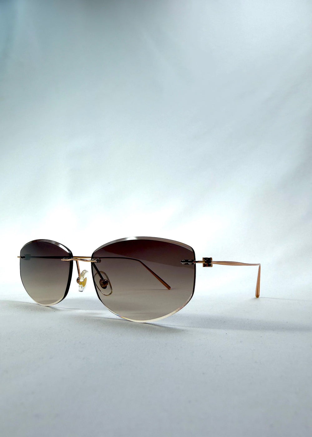 Three-quarter front view of Halo Trace sunglasses in Verdant Halo, featuring green-to-rose gradient nylon lenses and a lightweight titanium frame, showing the front shape and temple profile.