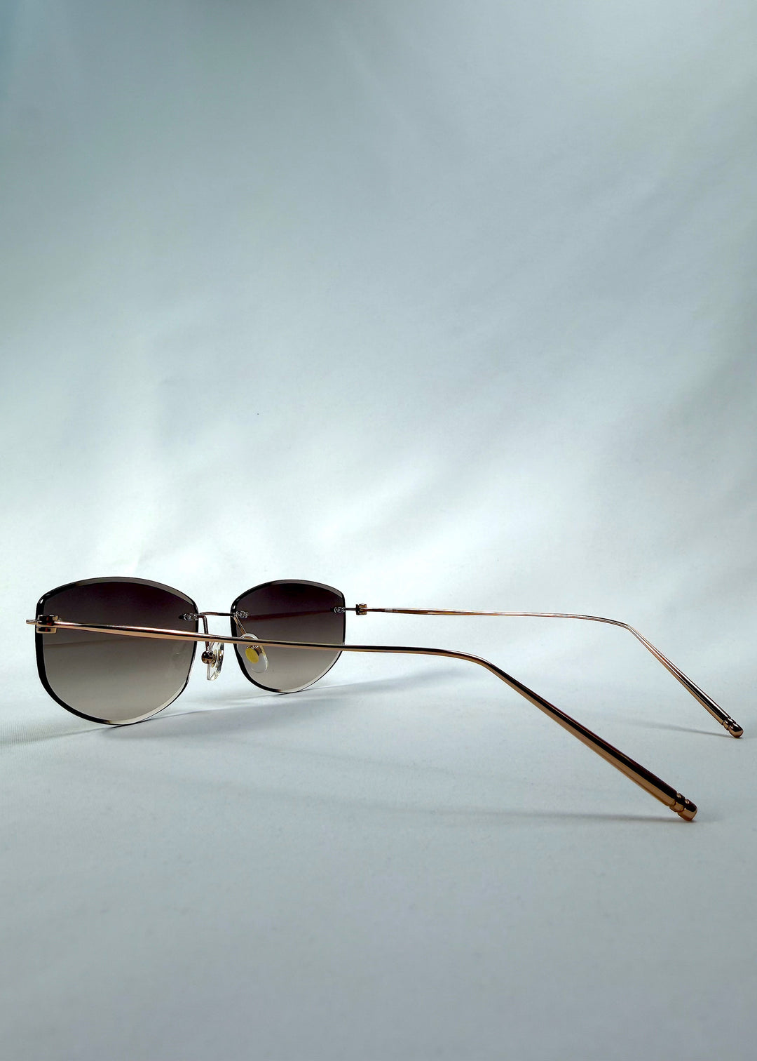Side-angle view of Halo Trace sunglasses in Verdant Halo, featuring green-to-rose gradient nylon lenses and a lightweight titanium frame, showing the lens shape and side temple profile.