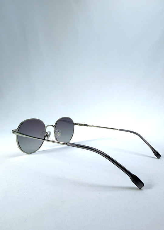 Back-angle view of AZE Liora Arc sunglasses in Moonlit Silver, featuring a silver-tone round frame and gray gradient lenses, showing the rear frame structure and temple alignment.