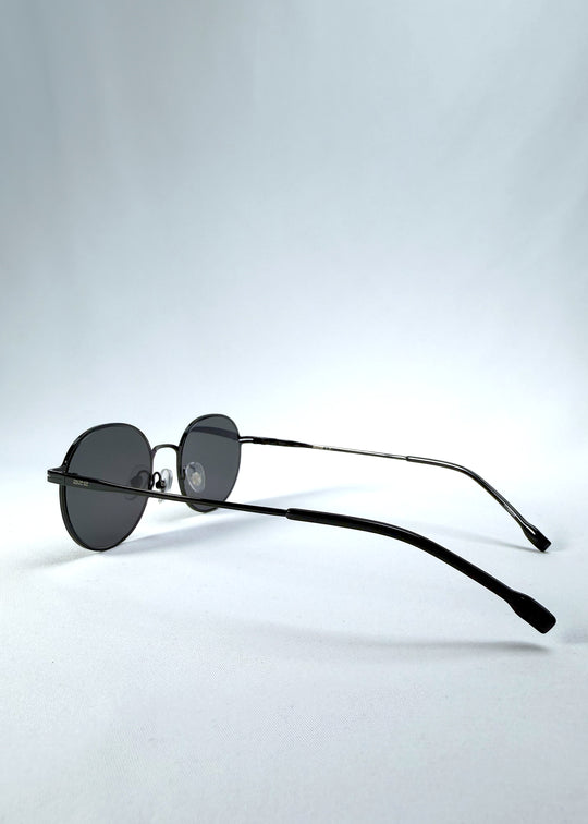 Back-angle view of AZE Liora Arc sunglasses in Obsidian Black, featuring a slim black round frame and smoky gray gradient lenses, showing the rear frame structure and temple alignment.