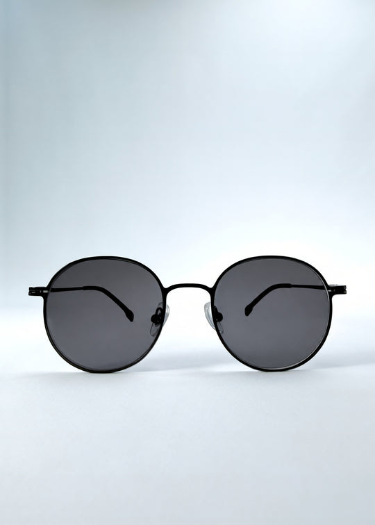 Front view of AZE Liora Arc sunglasses in Obsidian Black, featuring a slim black round frame and smoky gray gradient lenses, showing the full front silhouette.