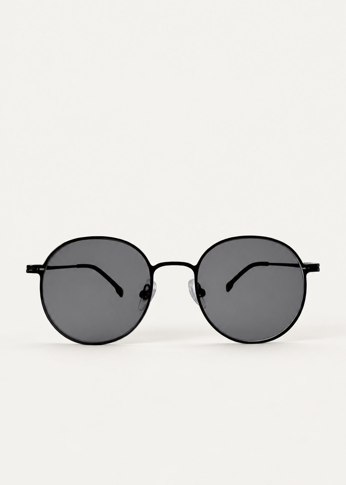 Front view of AZE Liora Arc sunglasses in Obsidian Black, featuring a slim black round frame and smoky gray gradient lenses, showing the full front silhouette.