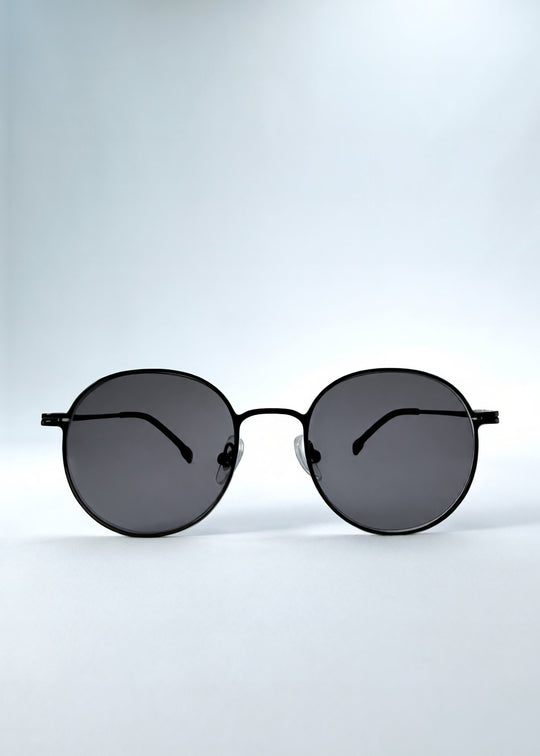 Front view of AZE Liora Arc sunglasses in Obsidian Black, featuring a slim black round frame and smoky gray gradient lenses, showing the full front silhouette. 