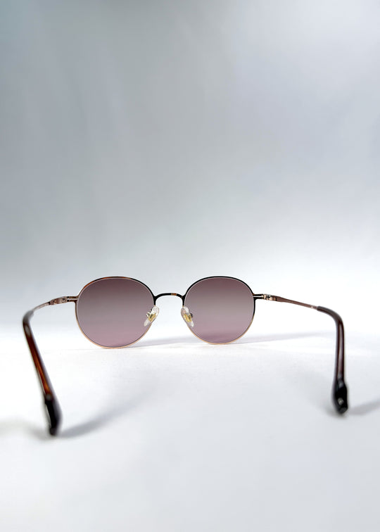Back view of AZE Liora Arc sunglasses in Rosé Dawn, featuring a rose-gold-tone round frame and soft rose gradient lenses, showing the inner frame and open temples.