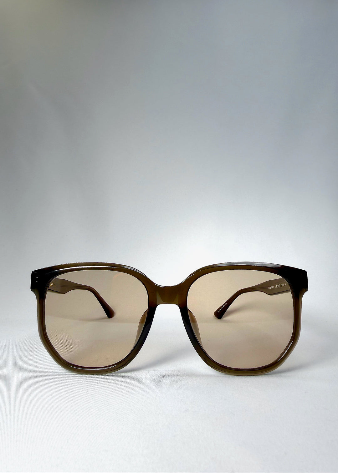 Front view of Lucent Rift in Sepia Veil showing the translucent grey-tea frame and warm beige-brown lenses. 