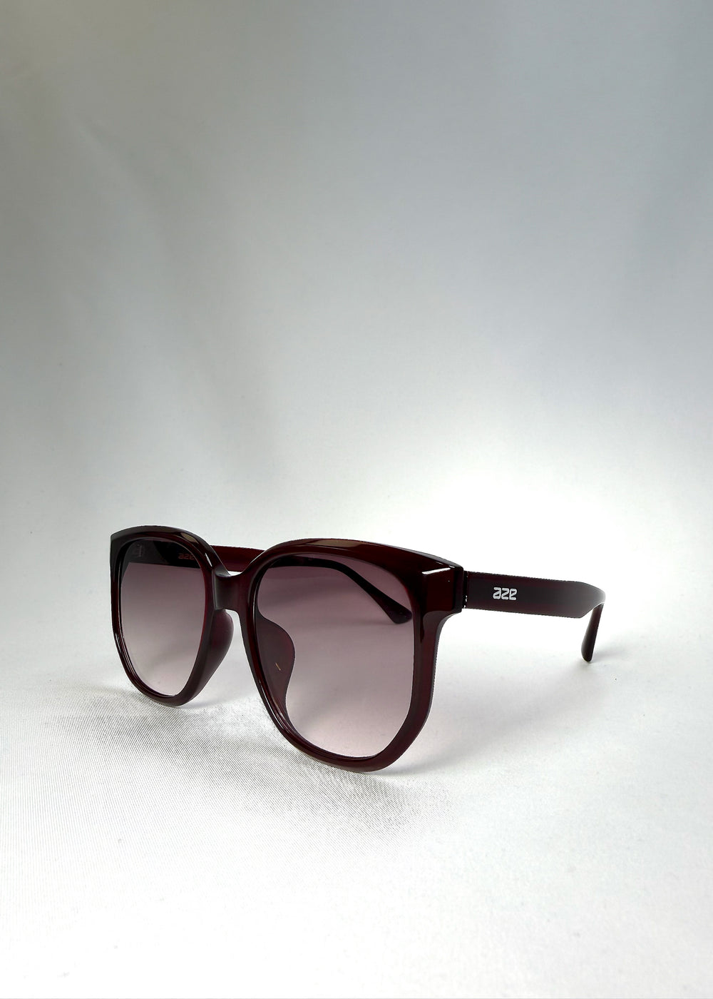 Angled front view of Lucent Rift in Velvet Eclipse highlighting the floating brow line and plum-tinted gradient lenses.
