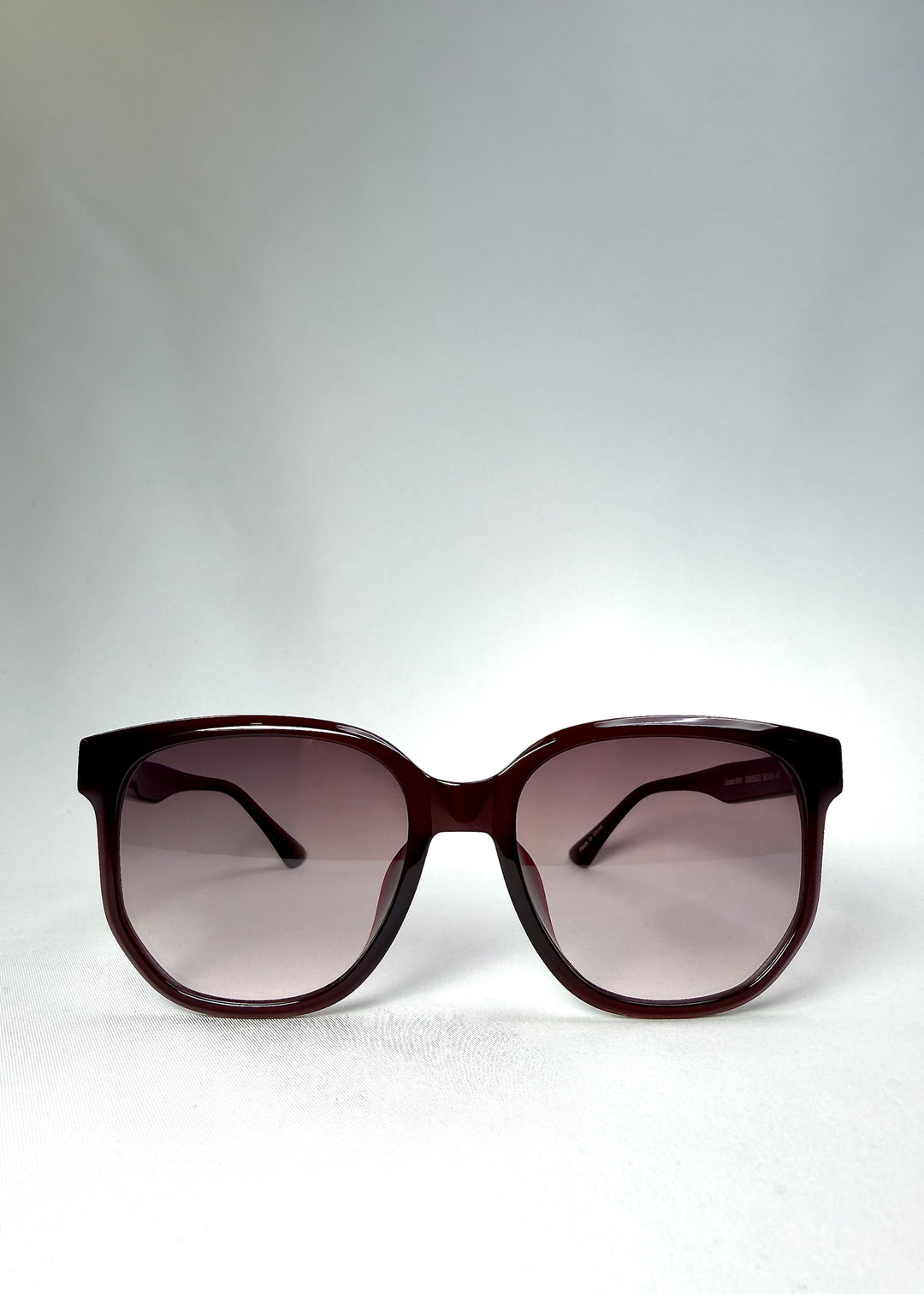 Front view of Lucent Rift in Velvet Eclipse showing the semi-transparent burgundy frame and gradient plum lenses.