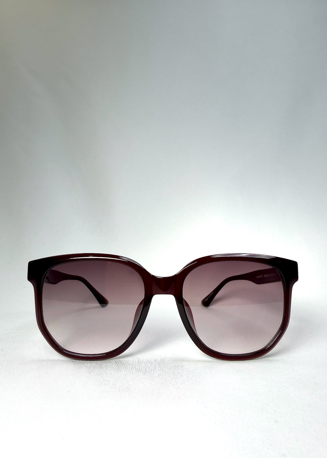 Front view of Lucent Rift in Velvet Eclipse showing the semi-transparent burgundy frame and gradient plum lenses. 