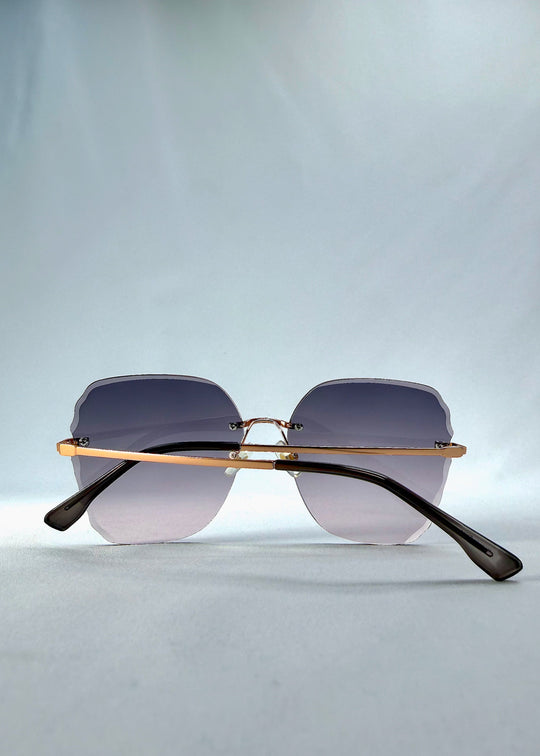 Folded back view of Lucera sunglasses in Misty Rosé, featuring rimless gold-tone frame and misty rose gradient lenses, showing the folded temples and back structure. 