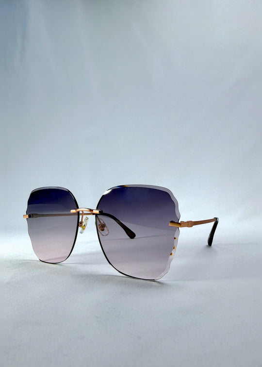 Three-quarter front view of Lucera sunglasses in Misty Rosé, featuring rimless gold-tone frame and misty rose gradient lenses, showing the front shape and temple profile. 