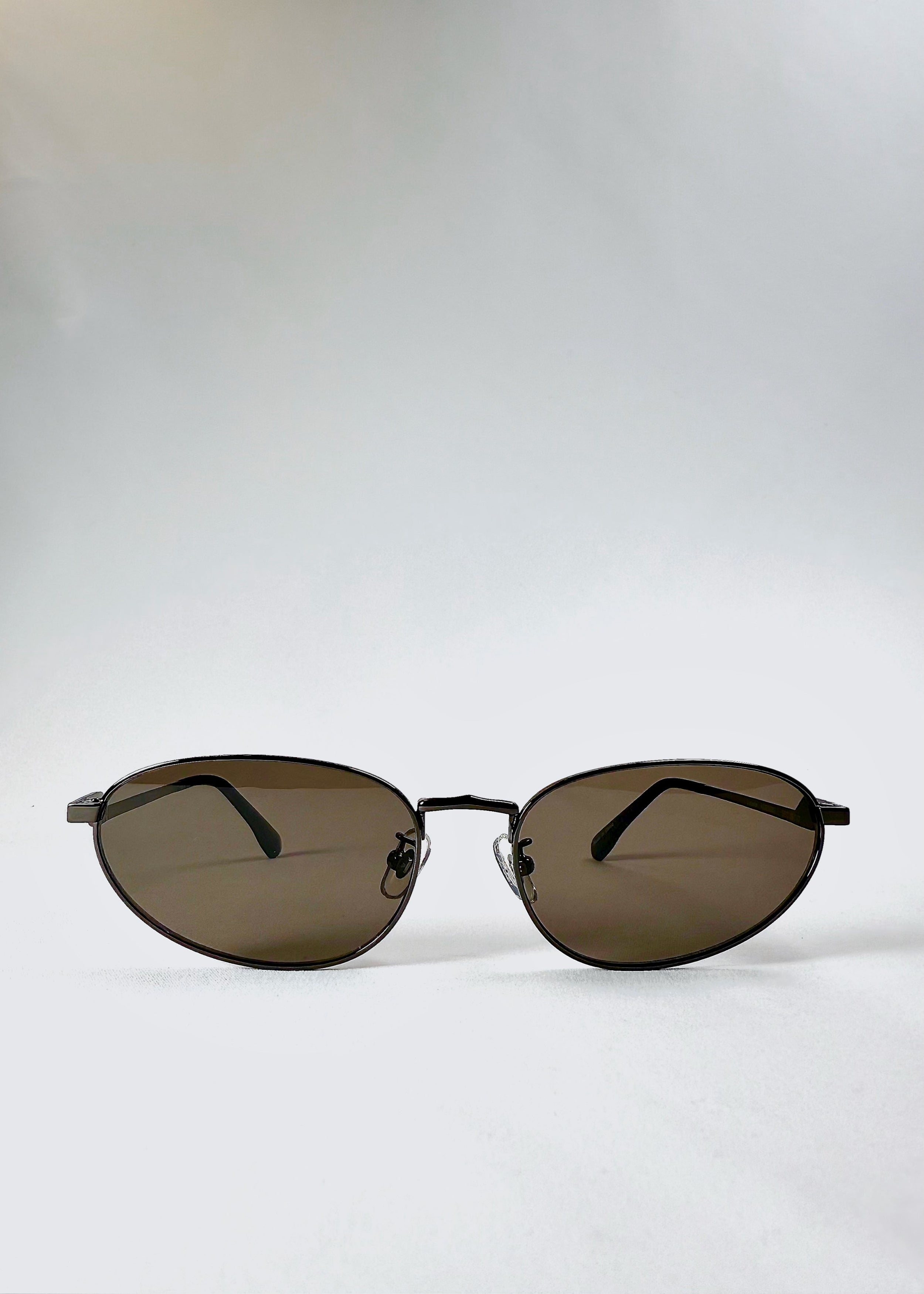 Front view of Lunaris - Iron Ember sunglasses showcasing the smoky grey-brown lenses and aviator silhouette.