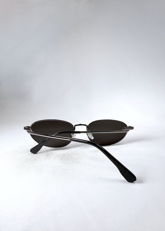 Back view of Lunaris - Moonlit Silver sunglasses in a folded position, with temples crossed over the silver frame. 