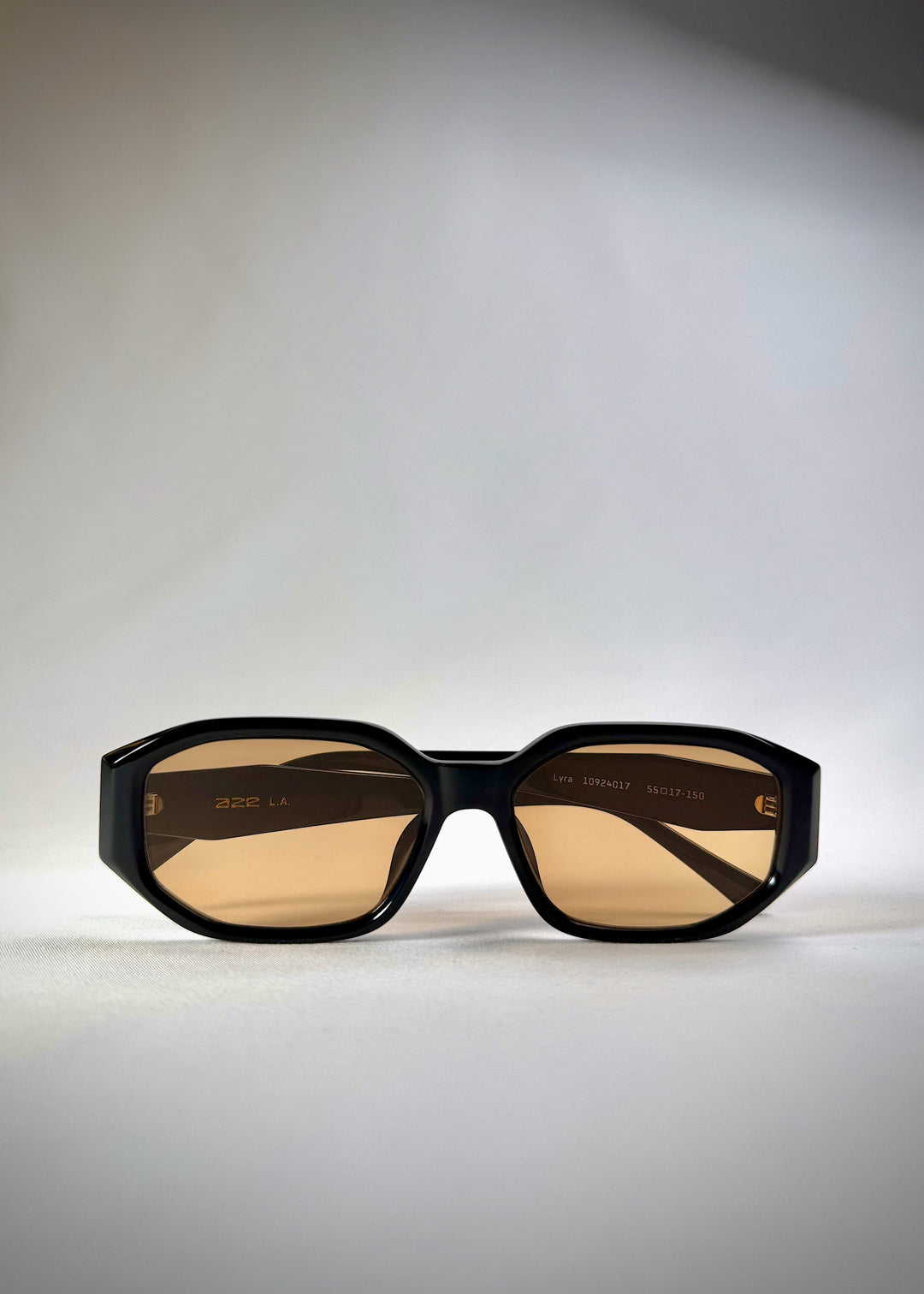 Folded view of Lyra sunglasses in Amber, featuring a glossy black acetate frame with amber-tinted lenses, showing the folded temples and frame profile. 