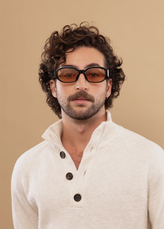 Male model wearing Lyra sunglasses in Amber with a cream knit sweater, facing forward. 