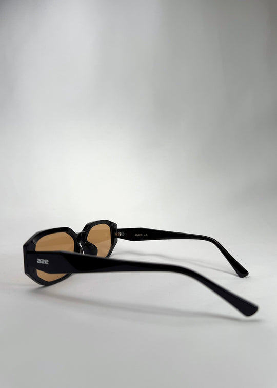 Side-angle view of Lyra sunglasses in Amber, featuring a glossy black acetate frame with amber-tinted lenses, showing the lens shape and temple profile. 