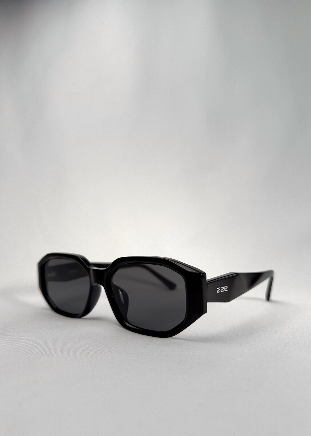 Three-quarter front view of Lyra sunglasses in Black, featuring a glossy black acetate frame, angular lens shape, and UV400 lenses, showing the front shape and temple profile. 