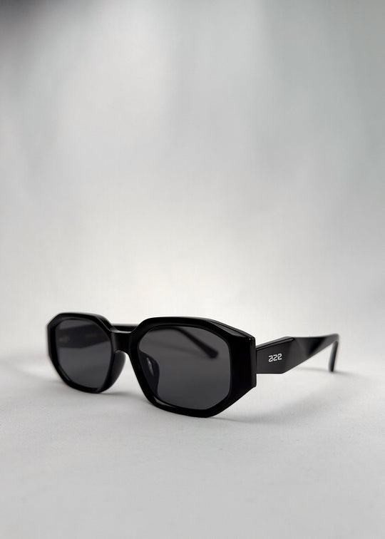 Three-quarter front view of Lyra sunglasses in Black, featuring a glossy black acetate frame, angular lens shape, and UV400 lenses, showing the front shape and temple profile. 