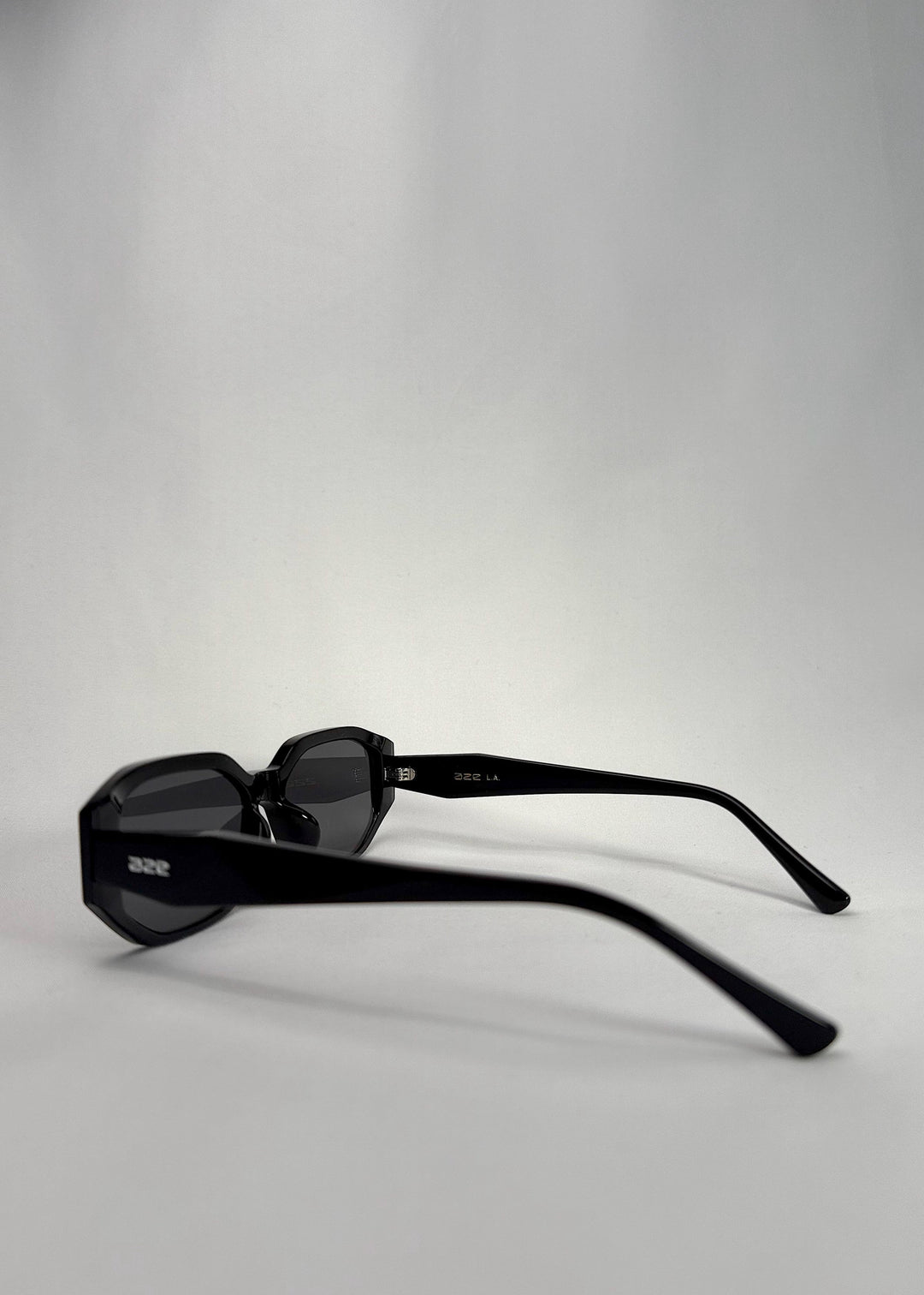 Side-angle view of Lyra sunglasses in Black, featuring a glossy black acetate frame, angular lens shape, and UV400 lenses, showing the lens shape and temple profile. 