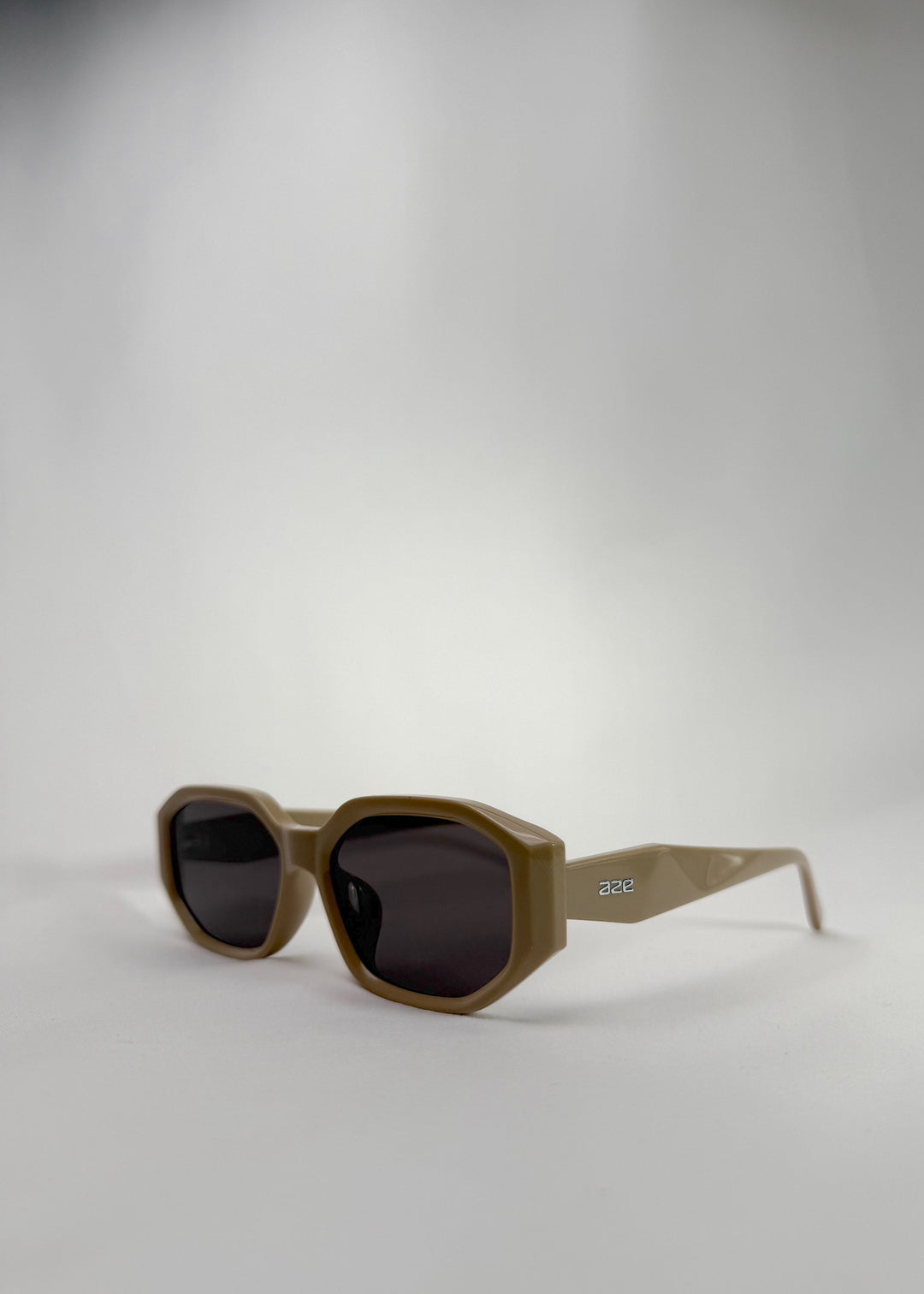 Three-quarter front view of Lyra sunglasses in Creamy Beige, featuring a sculpted acetate frame, angular lens shape, and UV400 lenses, showing the front shape and temple profile. 