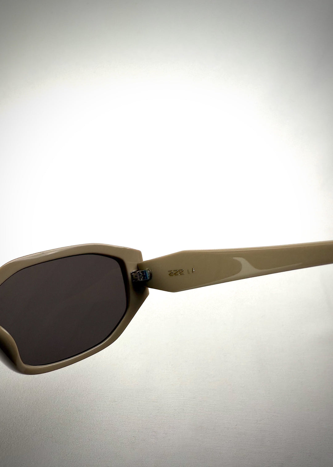 Close-up temple detail view of Lyra sunglasses in Creamy Beige, featuring a sculpted acetate frame, angular lens shape, and UV400 lenses, showing the temple arm and hinge area. 