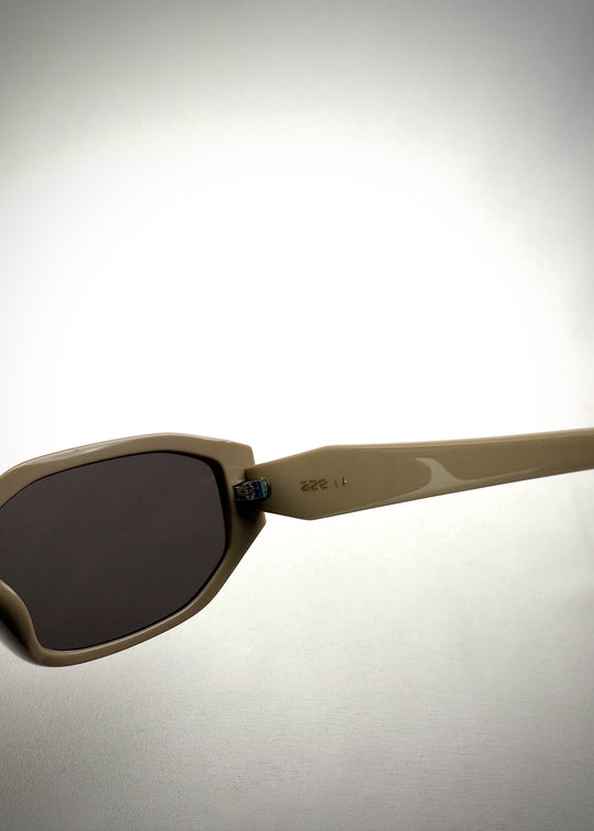 Close-up temple detail view of Lyra sunglasses in Creamy Beige, featuring a sculpted acetate frame, angular lens shape, and UV400 lenses, showing the temple arm and hinge area. 