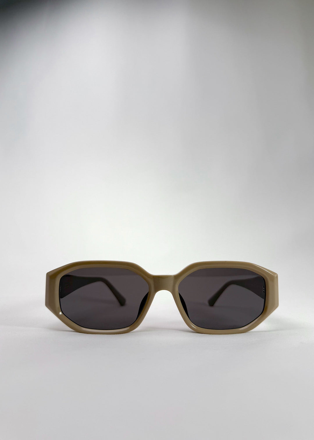 Front view of Lyra sunglasses in Creamy Beige, featuring a sculpted acetate frame, angular lens shape, and UV400 lenses, showing the full front silhouette. 