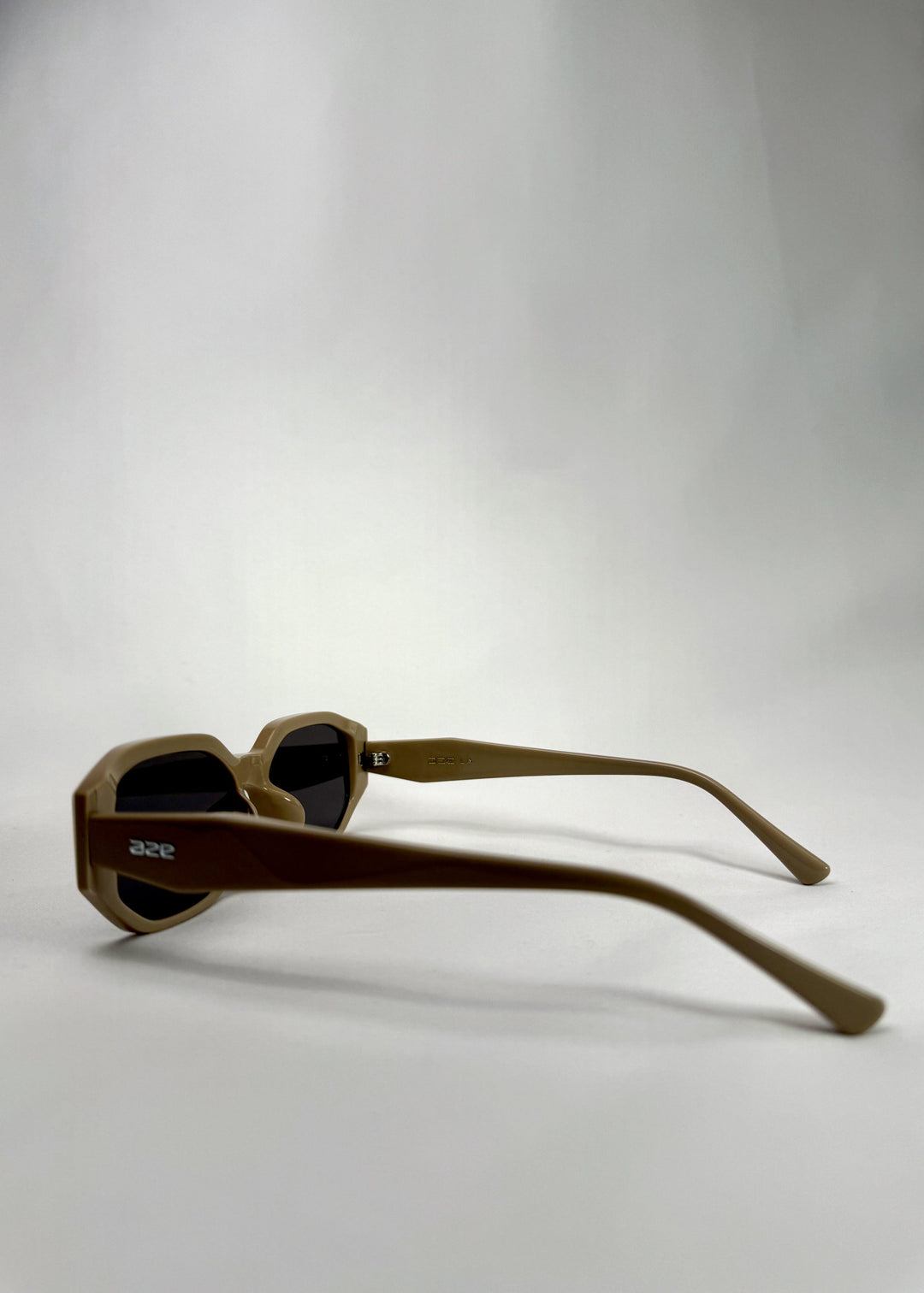 Side-angle view of Lyra sunglasses in Creamy Beige, featuring a sculpted acetate frame, angular lens shape, and UV400 lenses, showing the lens shape and temple profile. 