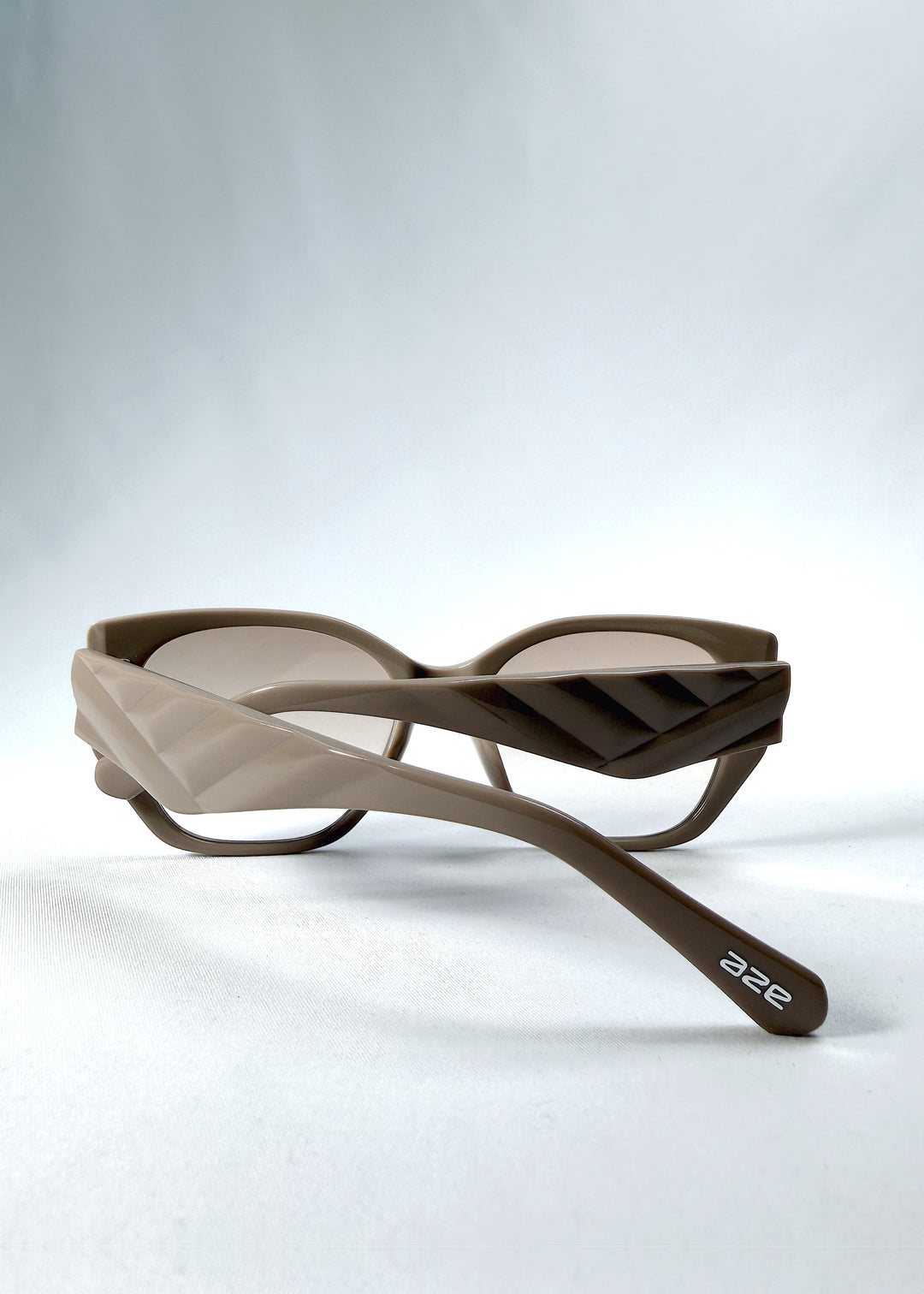 Folded view of Marlowe sunglasses in Mauve Mist, featuring a sculpted translucent mauve acetate frame and soft gradient lenses, showing the folded temples and frame profile.