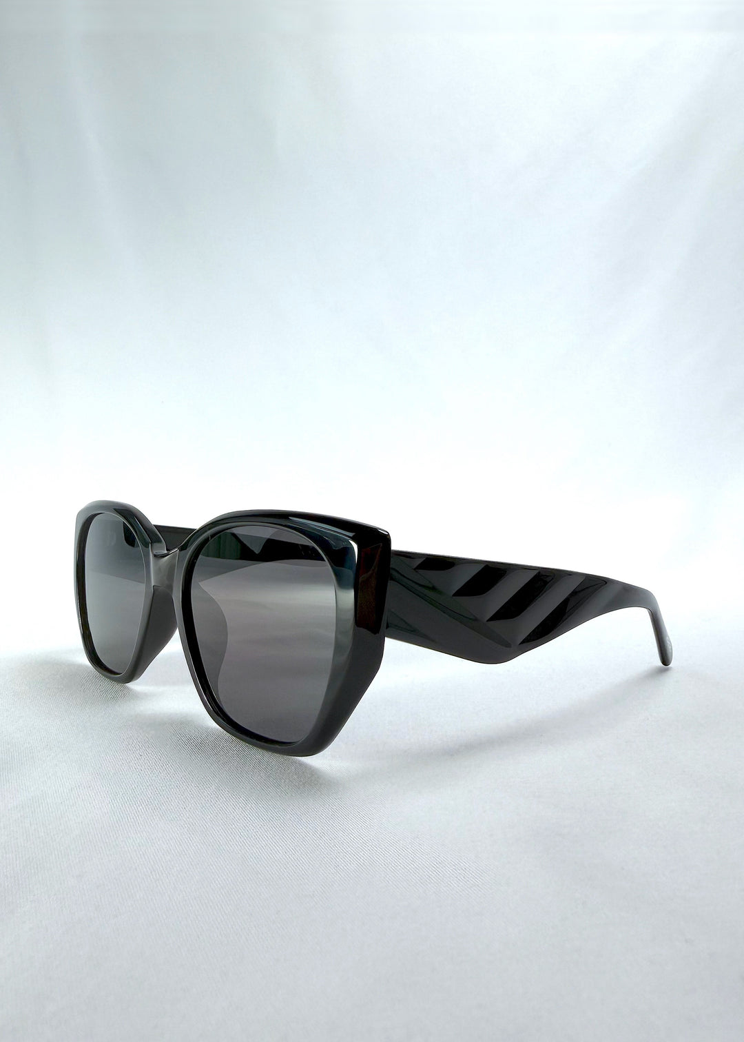 Three-quarter front view of Marlowe sunglasses in Obsidian Black, featuring glossy black acetate frame and dark lenses, showing the front shape and temple profile.