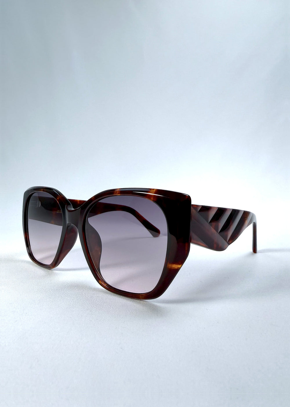 Three-quarter front view of Marlowe sunglasses in Tortoiseshell, featuring a sculpted tortoiseshell acetate frame and smoky gradient lenses, showing the frame shape and temple profile.