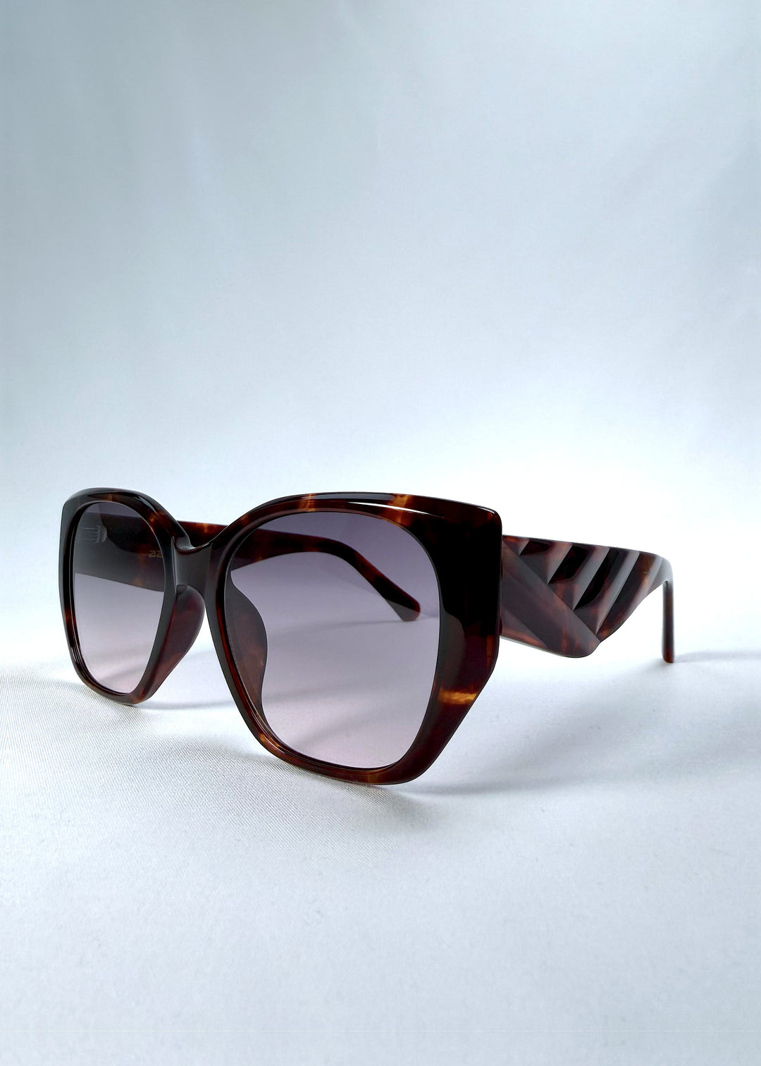 Three-quarter front view of Marlowe sunglasses in Tortoiseshell, featuring a sculpted tortoiseshell acetate frame and smoky gradient lenses, showing the frame shape and temple profile. 