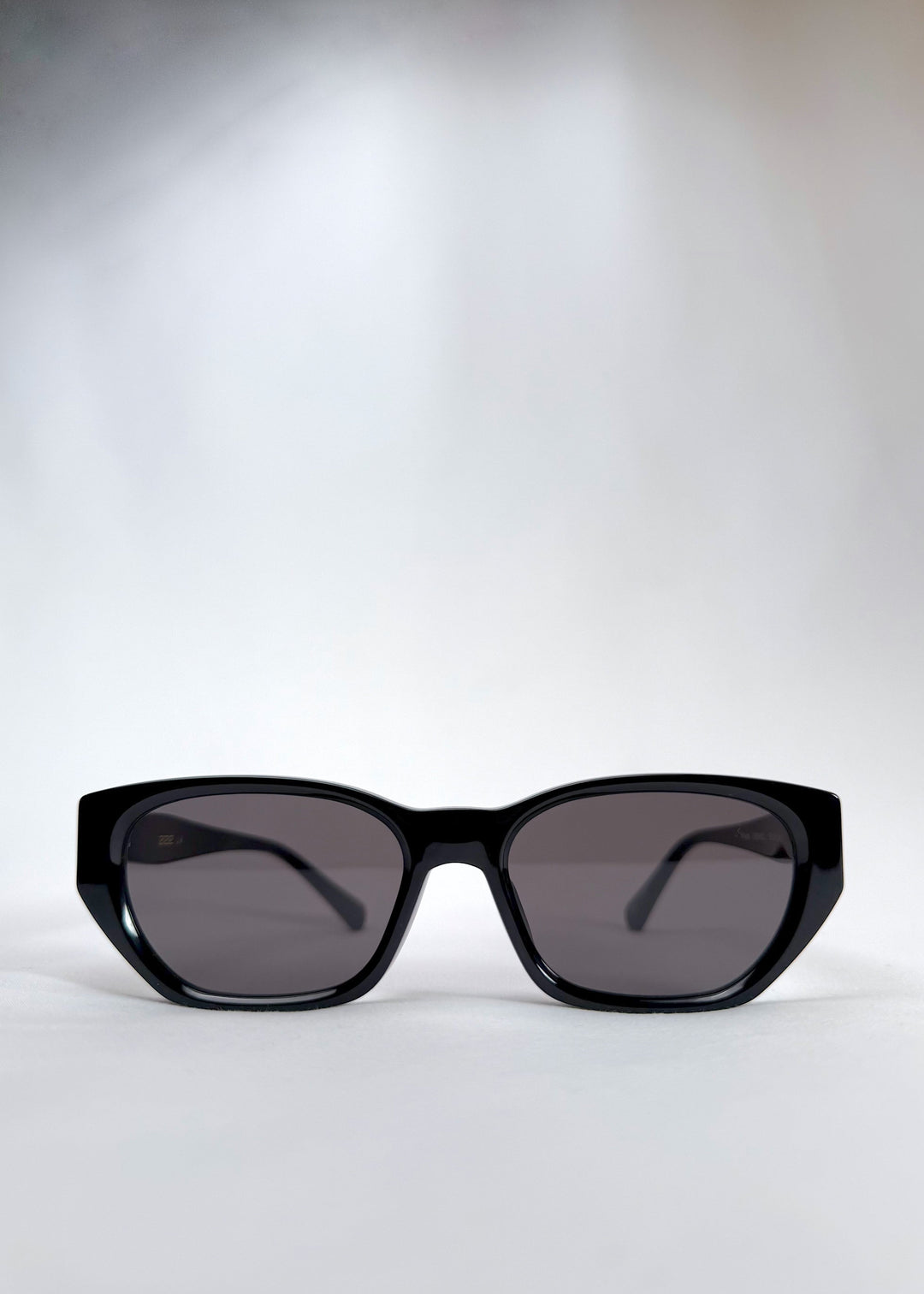 Front view of Mirach sunglasses in Black, featuring a glossy black acetate frame and gray UV400 lenses, showing the full front silhouette. 