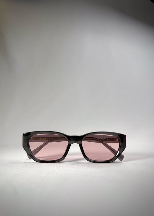 Folded view of Mirach sunglasses in Transparent Gray, featuring a smoke-gray translucent acetate frame and pink-tinted lenses, showing the folded temples and frame profile. 