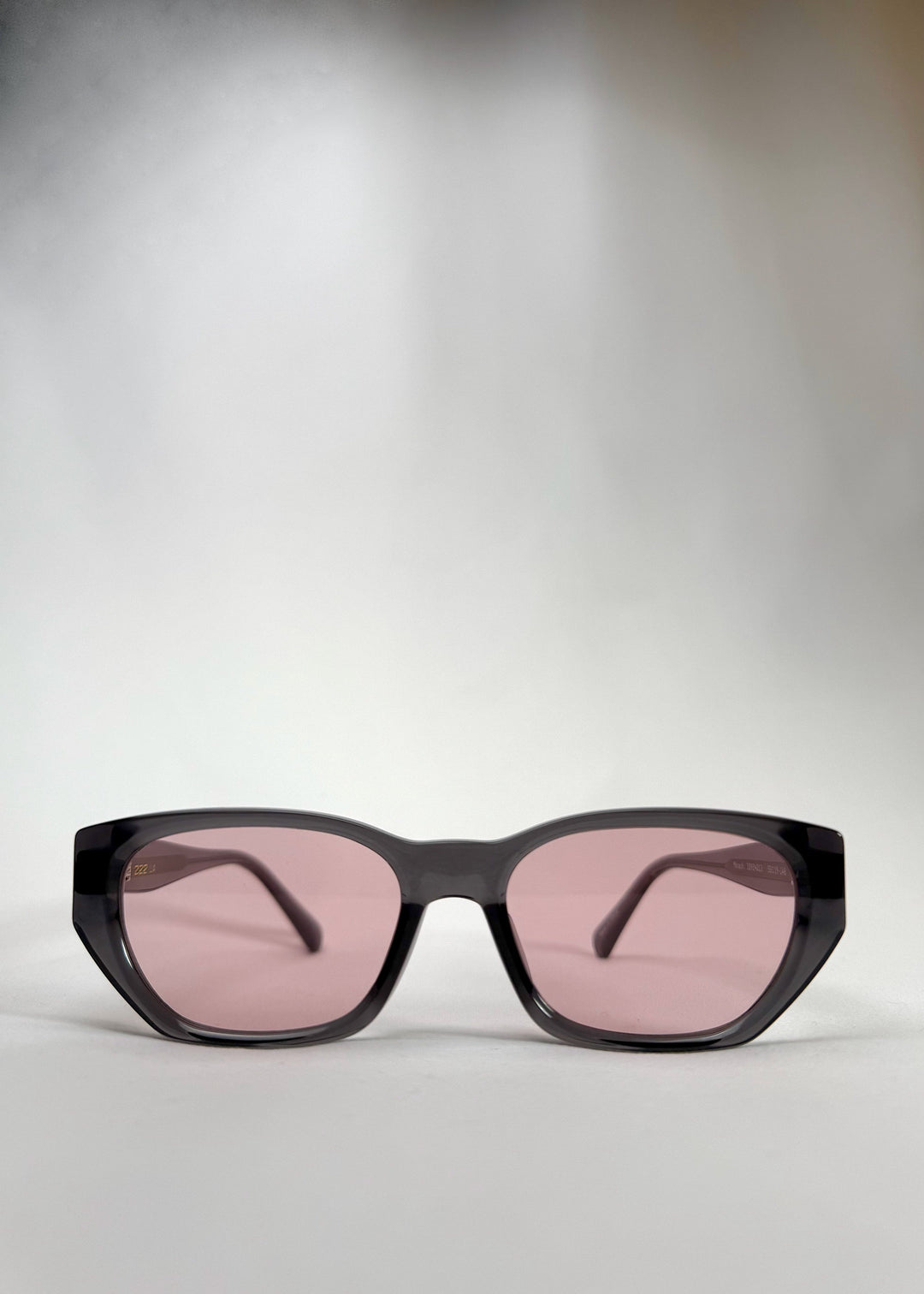 Front view of Mirach sunglasses in Transparent Gray, featuring a smoke-gray translucent acetate frame and pink-tinted lenses, showing the full front silhouette. 