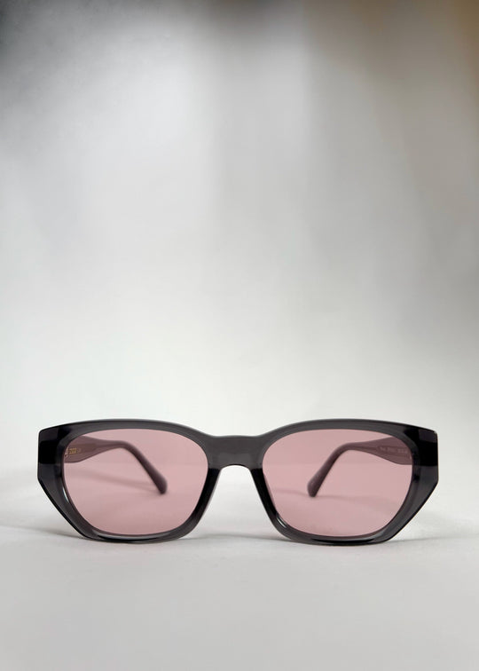 Front view of Mirach sunglasses in Transparent Gray, featuring a smoke-gray translucent acetate frame and pink-tinted lenses, showing the full front silhouette. 