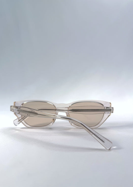 Folded view of Mirach sunglasses in Transparent White, featuring crystal-clear acetate frame and tea-tinted lenses, showing the folded temples and frame profile.
