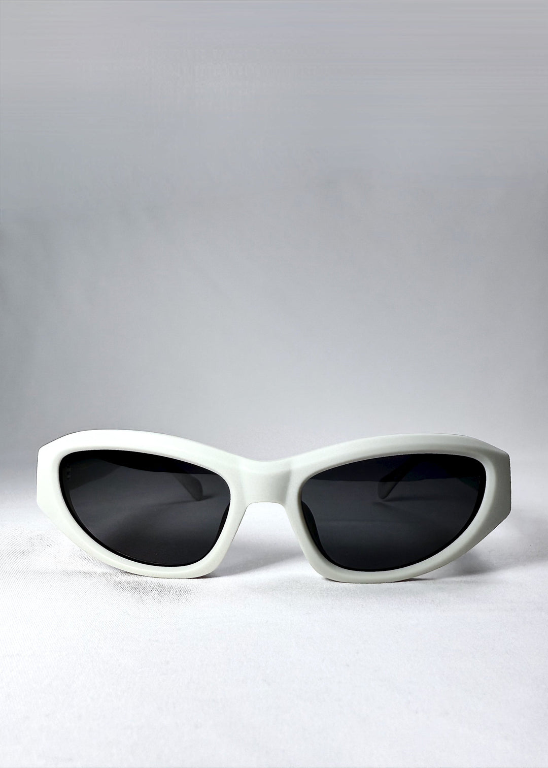 Front view of Nebula Shade in Glacial Ash showing its matte fog-white cat-eye frame and solid grey lenses. 