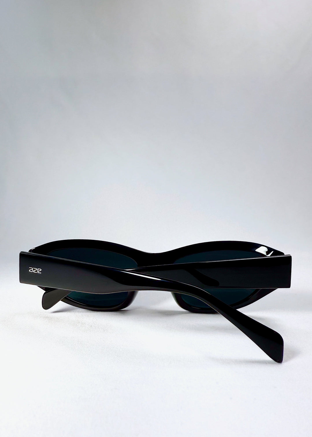 Folded view of Nebula Shade sunglasses in Obsidian Black, showing the compact folded structure and logo detail on the temples. 