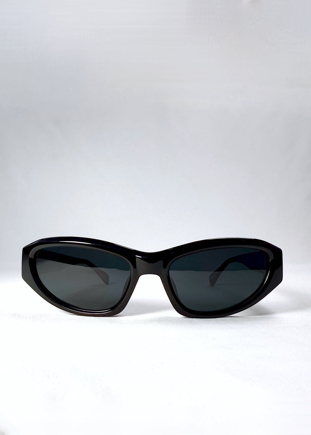 Front view of Nebula Shade sunglasses in Obsidian Black with smoky grey-green polarized lenses and glossy acetate cat-eye frame. 
