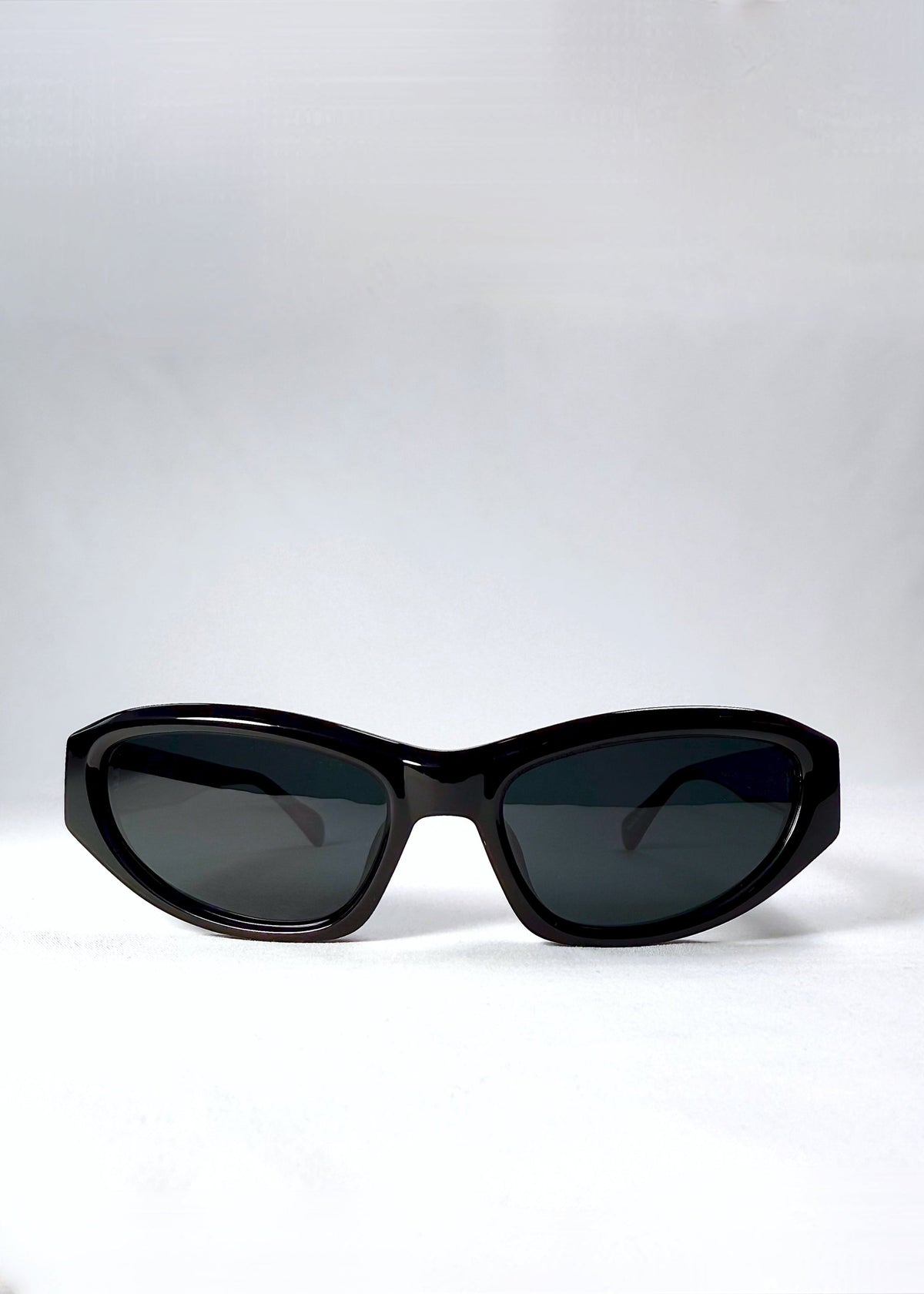 Front view of Nebula Shade sunglasses in Obsidian Black with smoky grey-green polarized lenses and glossy acetate cat-eye frame.