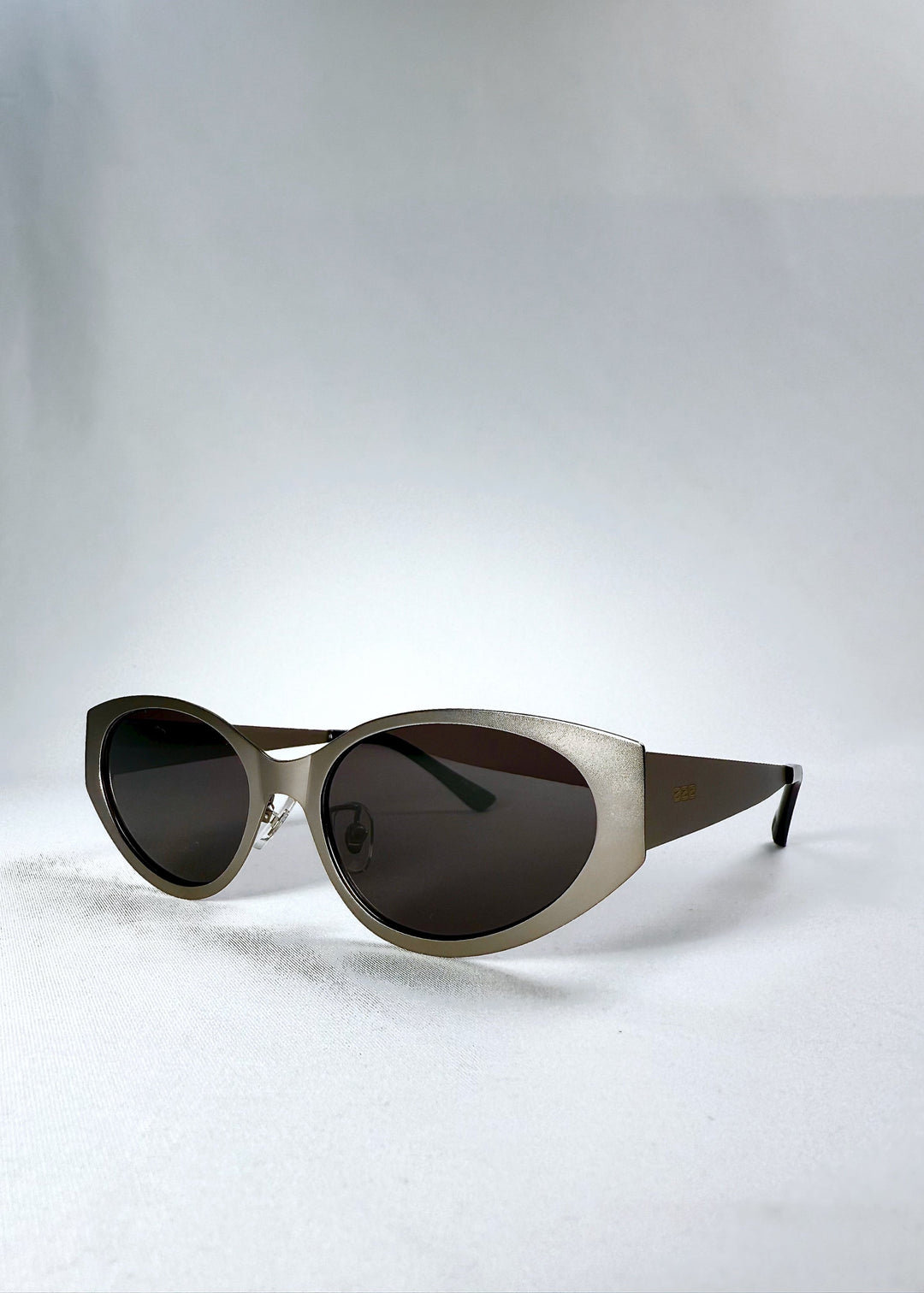 Three-quarter front view of Nyx sunglasses in Ash Steel, highlighting the sculpted cat-eye frame and matte finish. 