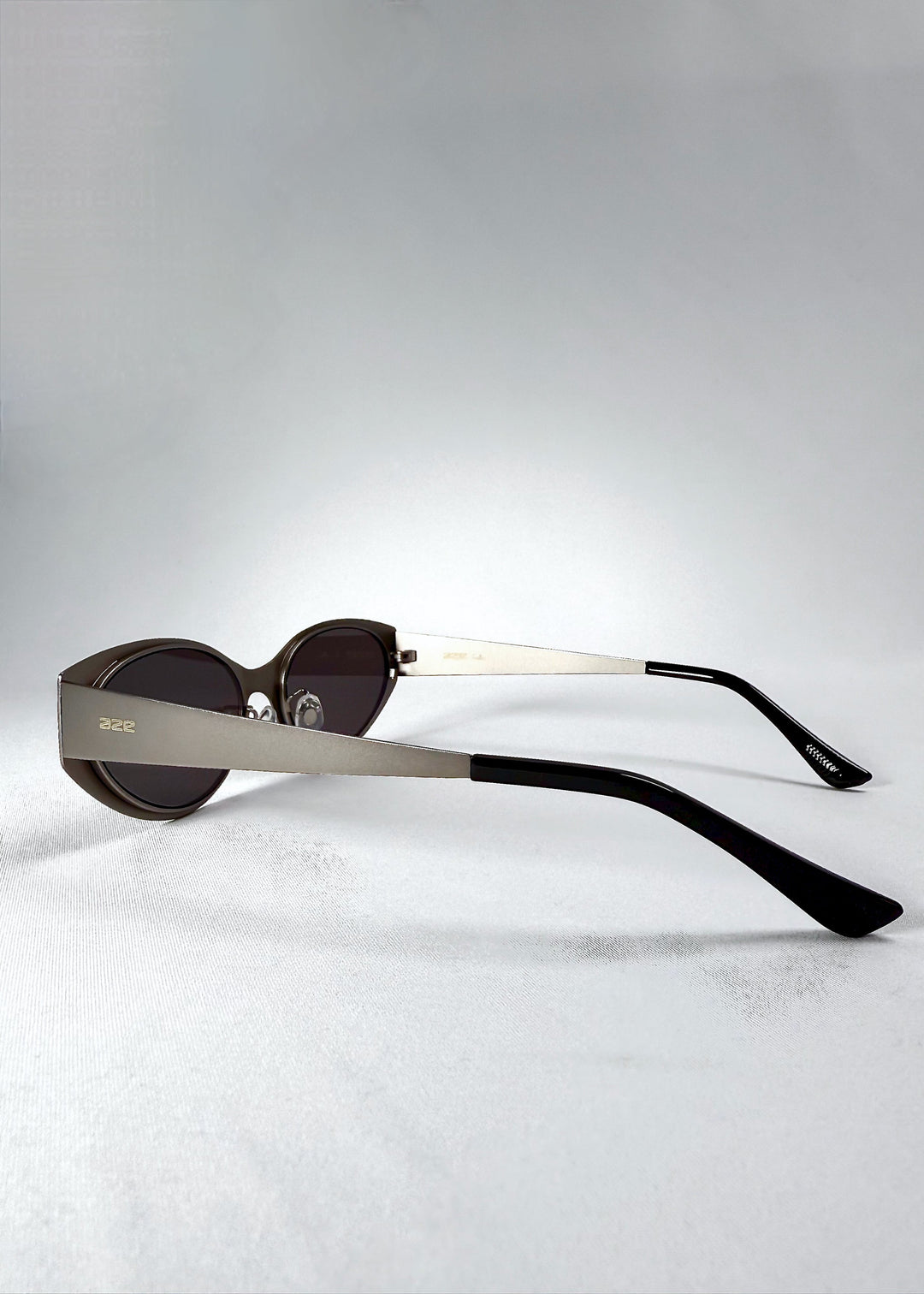 Side view of Nyx sunglasses in Ash Steel, showing the matte temple and engraved AZE logo. 