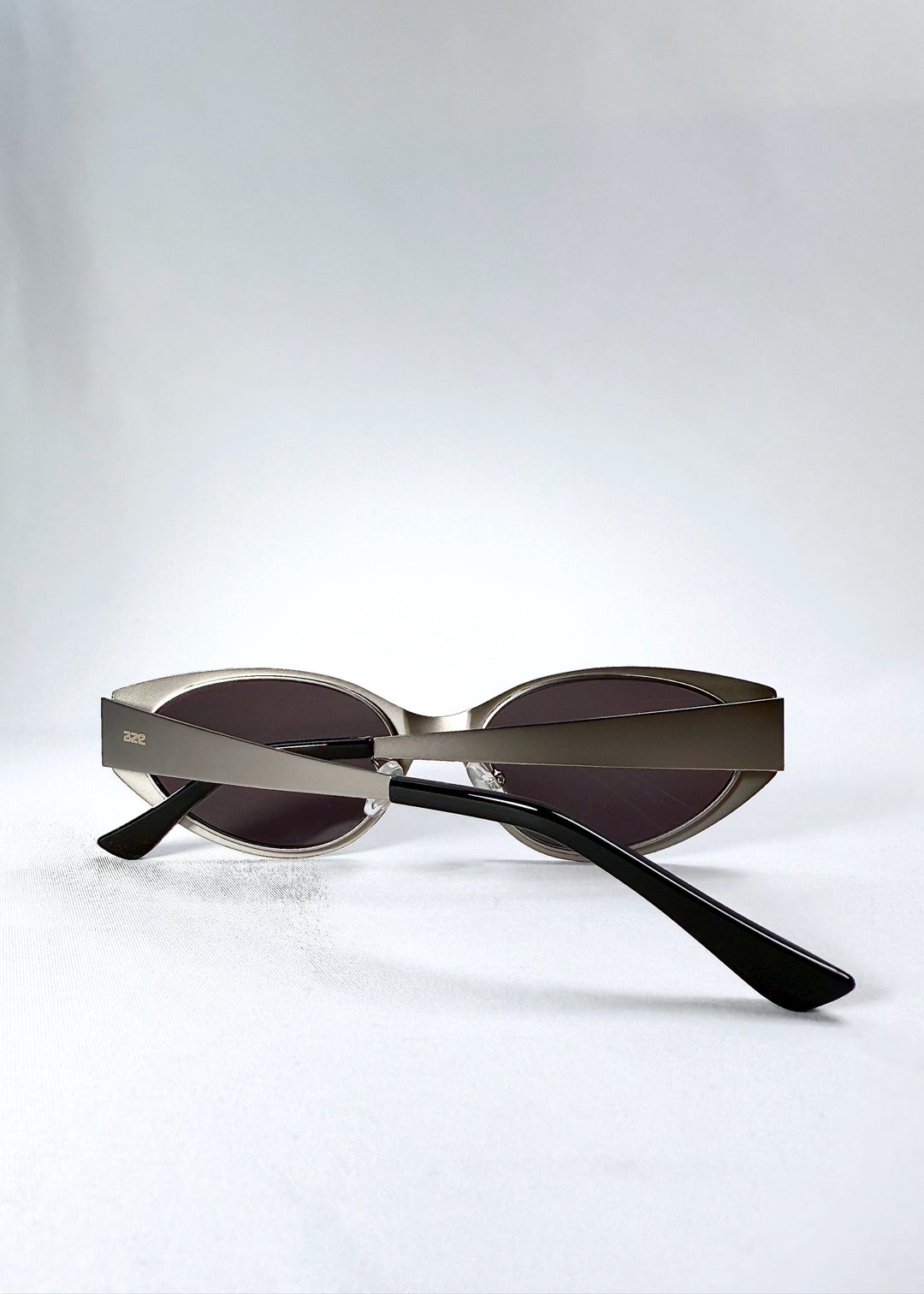 Close-up of the temple and engraved AZE logo on Nyx sunglasses in Ash Steel. 