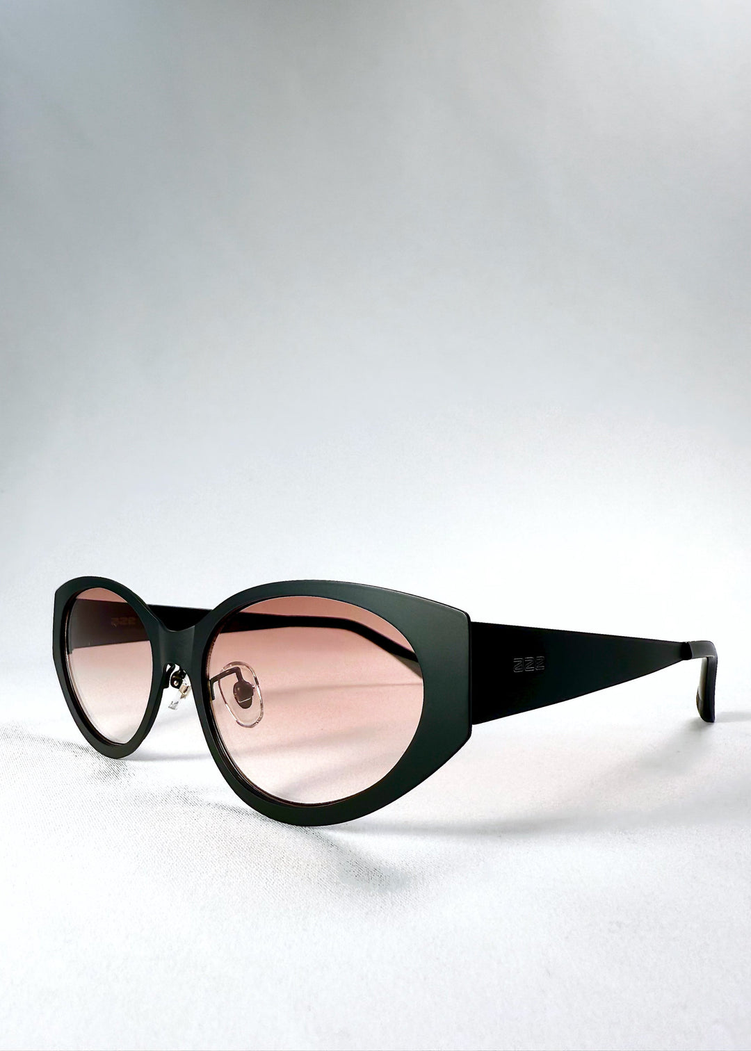 Three-quarter front view of Nyx sunglasses in Blush Eclipse, highlighting the cat-eye silhouette and adjustable nose pads. 
