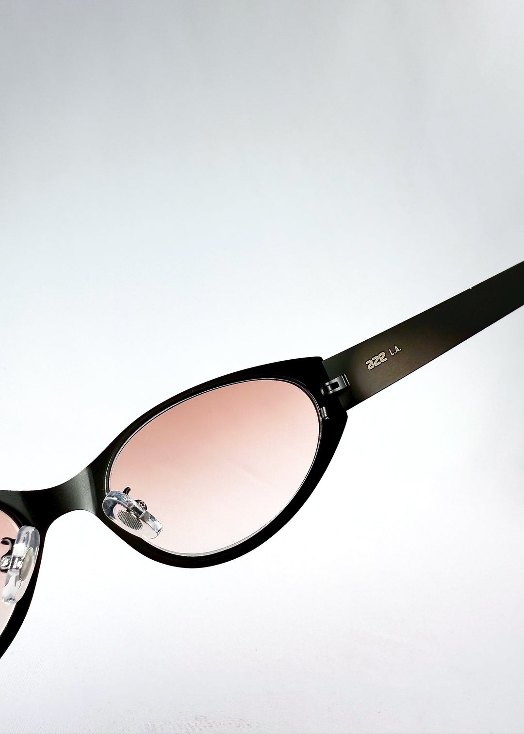 Inside detail view of Nyx sunglasses in Blush Eclipse, highlighting the pink lenses and adjustable nose pads. 