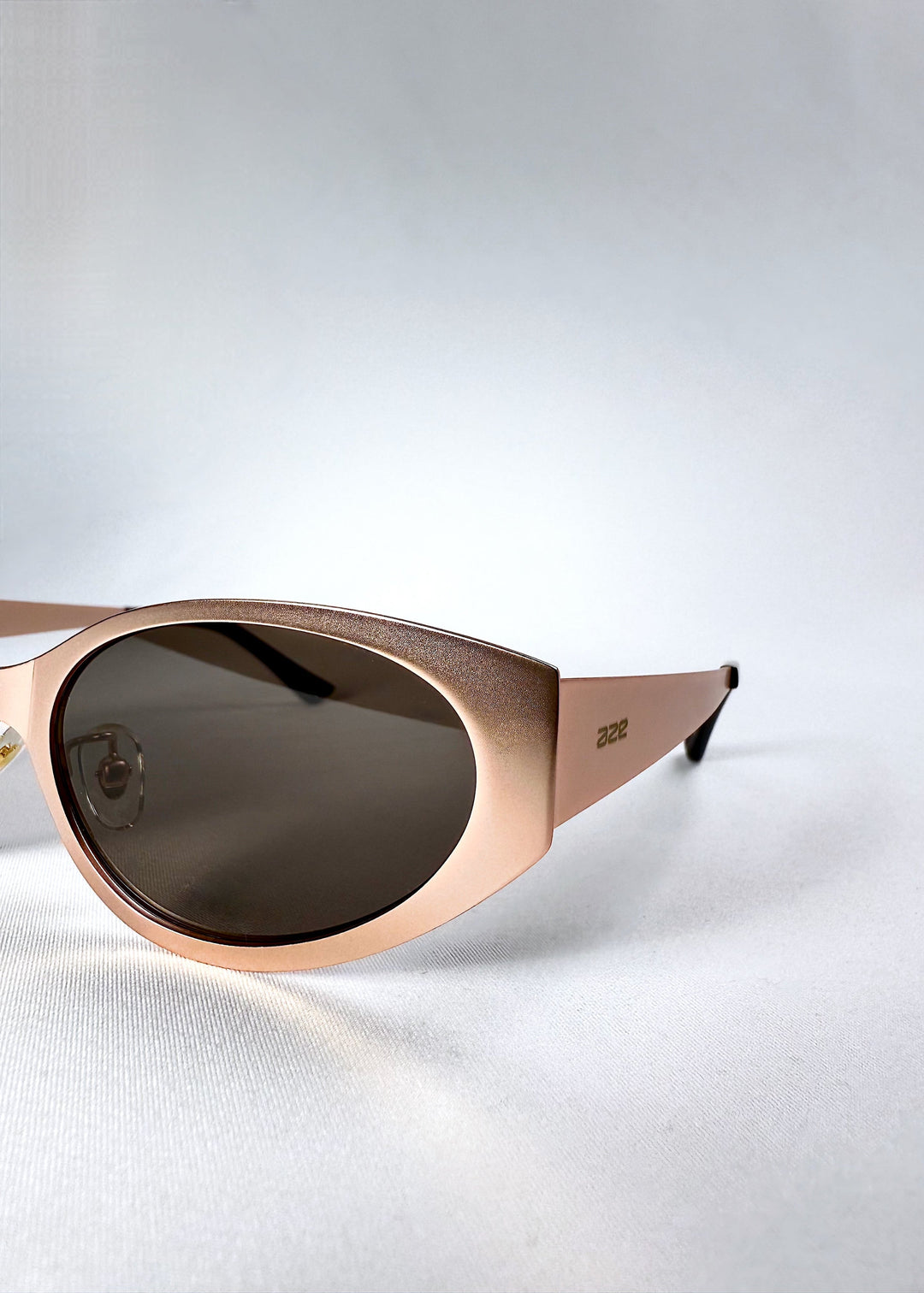 Angle close-up of Nyx sunglasses in Mocha Dusk, highlighting the cat-eye curvature and metallic finish. 