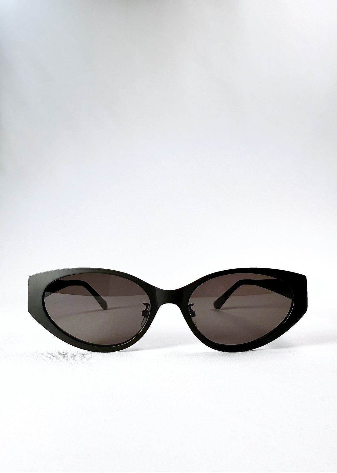 Front view of Nyx sunglasses in Shadow Black, showing the sculptural cat-eye frame and dark nylon lenses. 