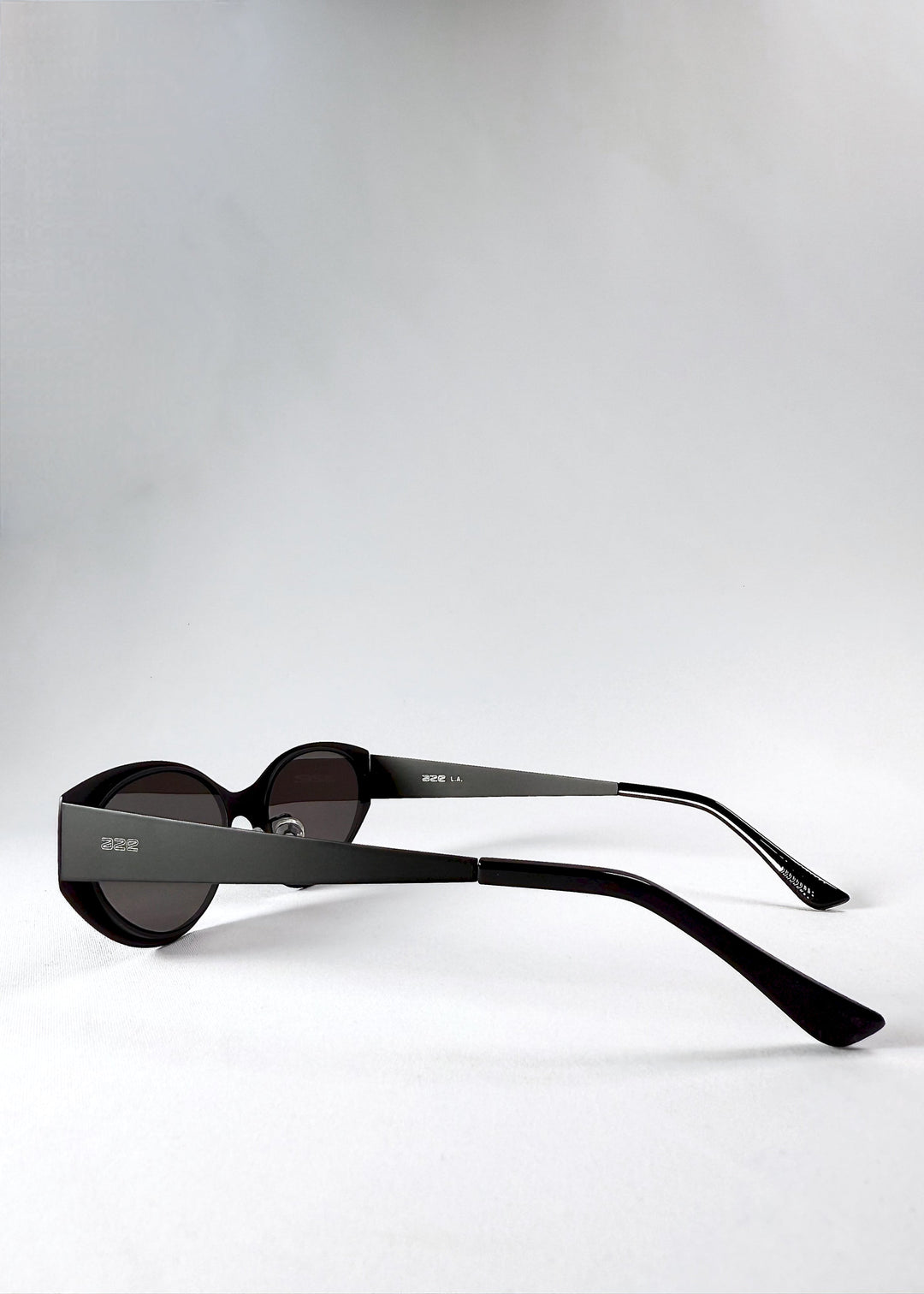 Side and temple view of Nyx sunglasses in Shadow Black, showing the stainless-steel frame and engraved AZE logo. 