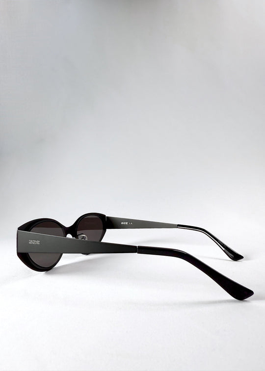 Side and temple view of Nyx sunglasses in Shadow Black, showing the stainless-steel frame and engraved AZE logo. 