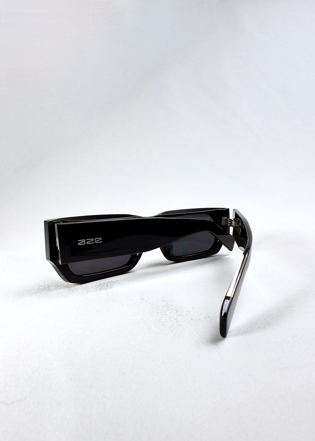 Folded view of Oblivion Trace in Obsidian Black, showcasing the sharp rectangular silhouette and Aze logo on the temple. 